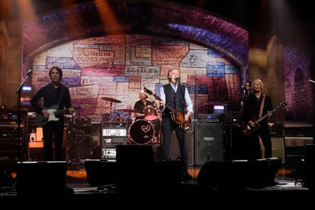 A band on stage with a graffiti wall behind them