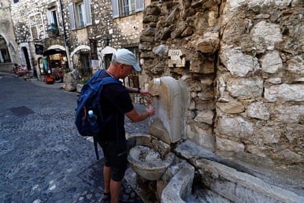 A man fills a bottle with water from a fountain