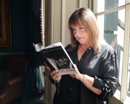 A woman reading a book as she stands by a window