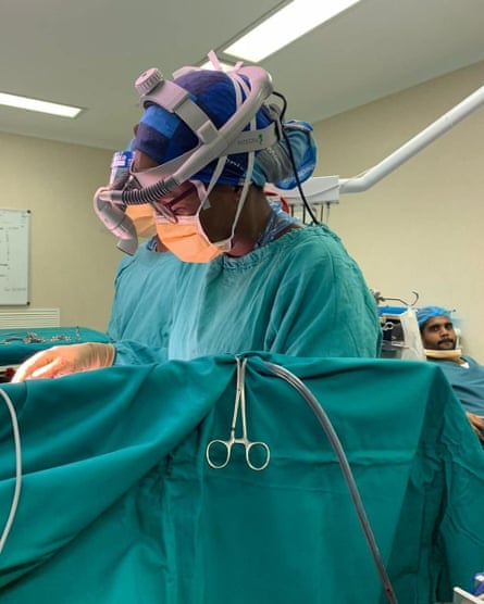 A woman performing a surgery behind a screen