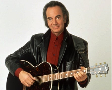 Neil Diamond in a leather jacket, dark red shirt and an acoustic guitar