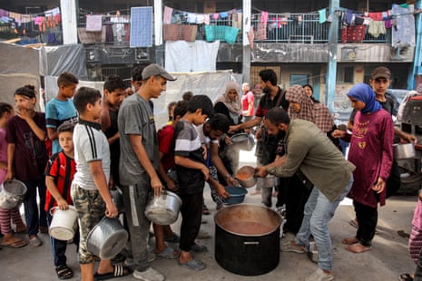 Children queue with pots to receive food aid from a kitchen at the Abu Zeitun school run by Unrwa in the Jabalia camp for Palestinian refugees in the northern Gaza Strip on Thursday.