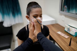Vitoria Bueno, a 16-year-old dancer whose genetic condition left her without arms, uses her foot to apply makeup to a teammate from the Andrea Falsarella ballet academy at the Inatel Theatre.