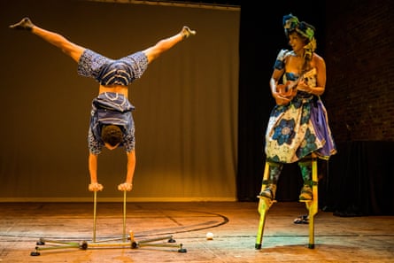 a person does a handstand while another person stands on stilts