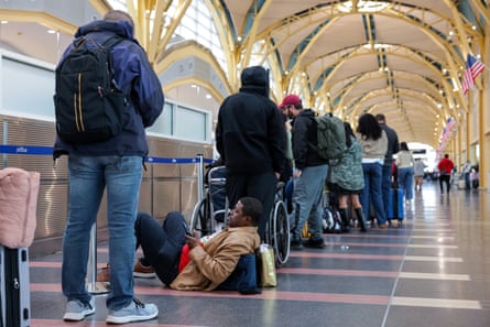 people wait with bags in long line at airport