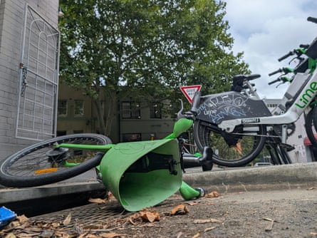 Several Lime ebikes parked in a row, with one fallen on the ground