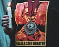 A person holds a candle while wearing a George Floyd T-shirt that reads 'Please, I can't breathe'
