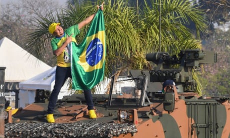BRAZIL-POLITICS-BOLSONARO-INDEPENDENCE-DAY<br>A supporter of Brazilian President Jair Bolsonaro holds a national flag while standing on a military vehicle, outside the Alvorada Palace, during the Independence Day celebrations in Brasilia, on September 7, 2021. - Fighting record-low poll numbers, a weakening economy and a judiciary he says is stacked against him, President Jair Bolsonaro has called huge rallies for Brazilian independence day Tuesday, seeking to fire up his far-right base. (Photo by EVARISTO SA / AFP) (Photo by EVARISTO SA/AFP via Getty Images)
