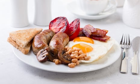 An English breakfast with fried eggs, sausages, white beans, bacon, mushrooms, toast and tomato.