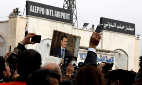 People hold up a picture of Syria's President Assad at Aleppo international airport after it reopened for the first time in years in February 2020