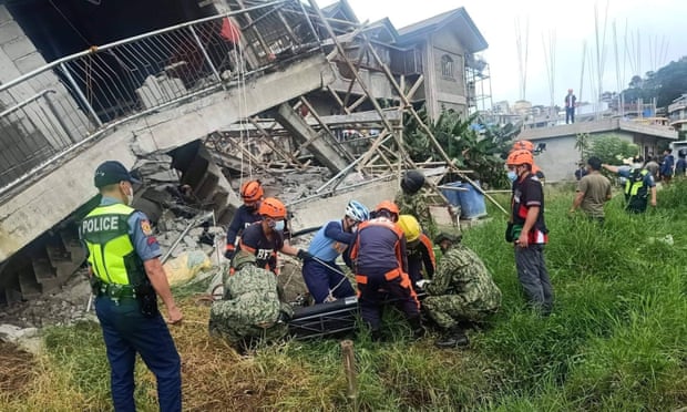     救助者と警官は地震の余波で倒壊した建物に取り組んでいます