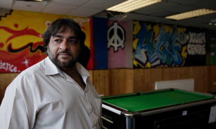 Hanif Qadir standing in a room with a pool table and graffiti-style art on the wall