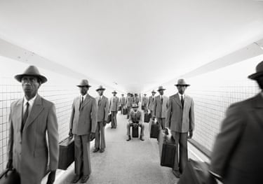 Majority Rule (tunnel) 2014. A monochrome image of repeated images of a man in a grey suit and hat holding a briefcase in a pedestrian tunnel.