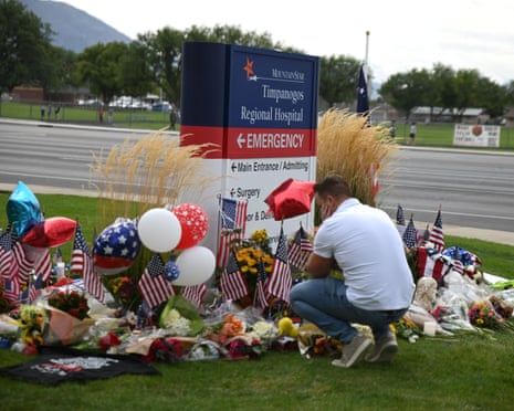 A man observes a floral memorial for Charlie Kirk outside Timpanogos hospital in Orem, Utah.