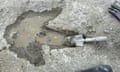 A trowel is propped up in a water-filled dinosaur print.