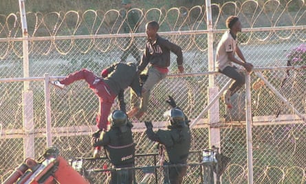 Police help people down from the the border fence between Morocco and Ceuta, Spain.