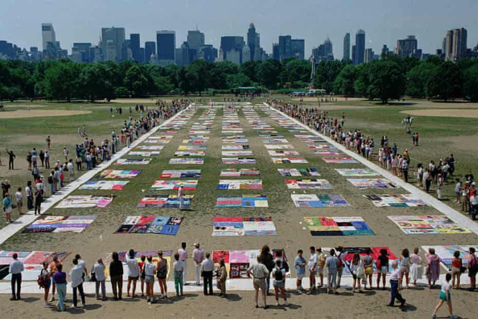 People watch as almost 1,500 quilt panels bearing the names of New York area residents who have died of AIDS are unfolded on the Great Lawn in New York’s Central Park on 25 June 1988.