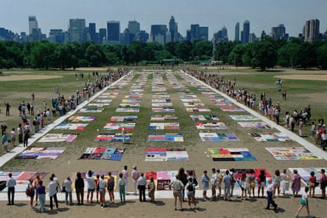 People watch as almost 1,500 quilt panels bearing the names of New York area residents who have died of AIDS are unfolded on the Great Lawn in New York’s Central Park on 25 June 1988.