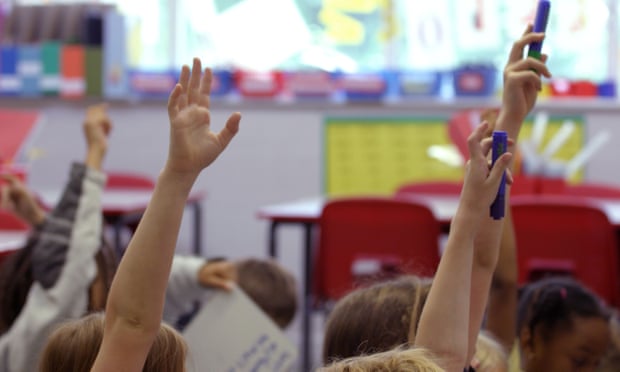 Children put their hands in the air during a lesson at a school