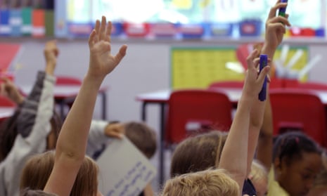 Children put their hands in the air during a lesson.