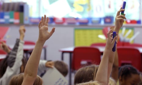 Children put their hands in the air during a lesson at a junior school