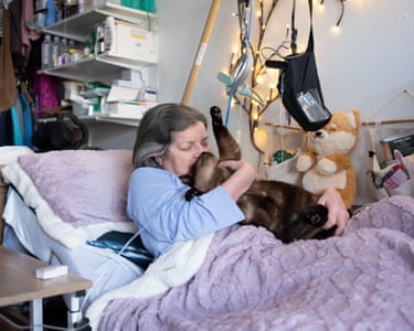 Christine Koberg hugs her cat from a hospital bed at home