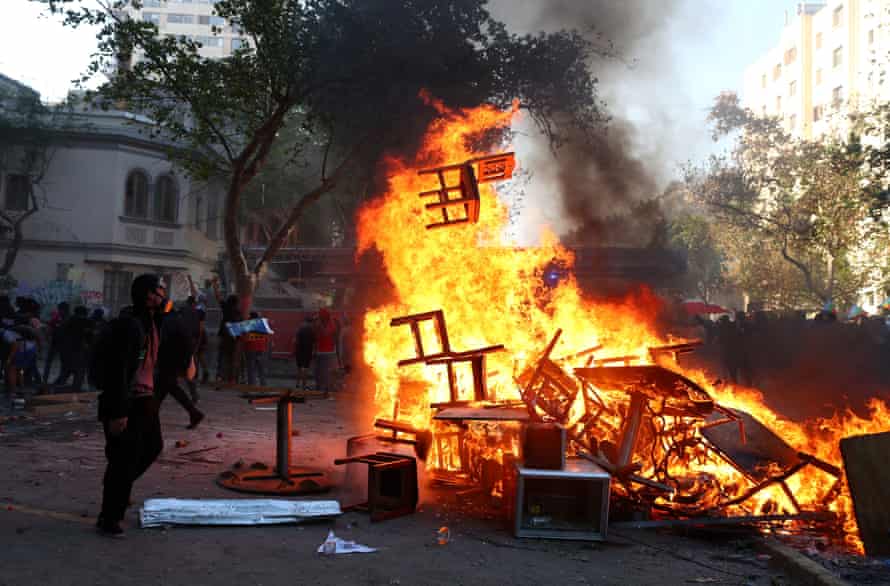 A demonstrator watches a burning barricade during a protest in Santiago, Chile, 12 November