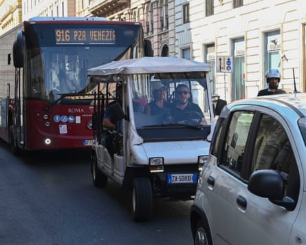 A golf cart between a car and a bus
