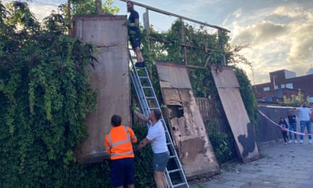 Contractors dismantle the billboard in Cricklewood, with the cat visible on a panel on the right.