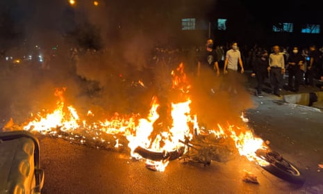Demonstrators gather near a motorbike on fire during a protest in Tehran on 19 September over the death of Mahsa Amini