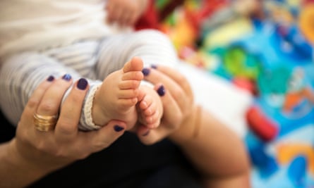 Older mother's hands holding baby's feet