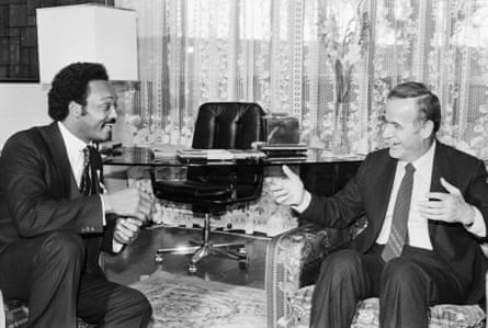 A Black man and a white man in armchairs appear to be having a lively and friendly conversation with each other.