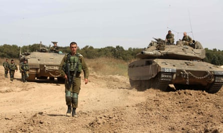 Israeli soldiers stand guard next to a tank