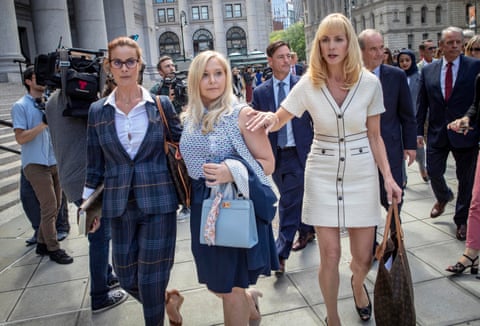Sarah Ransome, left, and Virginia Roberts Giuffre, centre, with several men in suits walking behind them and a camera on the left