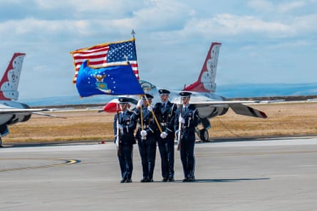 men in military uniforms stand outside by planes holding flags