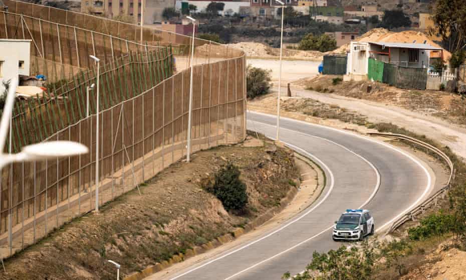 A police car patrols the Spanish side of the border fence separating the Melilla enclave from Morocco.