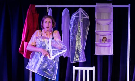 A woman holding a clothing cover and looking scared, with a rail of clothing behind her, in a scene from Breathless