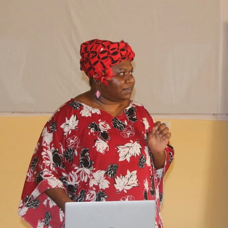 A woman wearing a red headscarf and flora dress gives a presentation