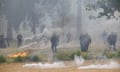 French riot police officers stand guard amid smoke from the teargas and trees during the protest
