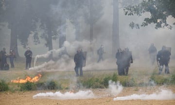 French riot police officers stand guard amid smoke from the teargas and trees during the protest