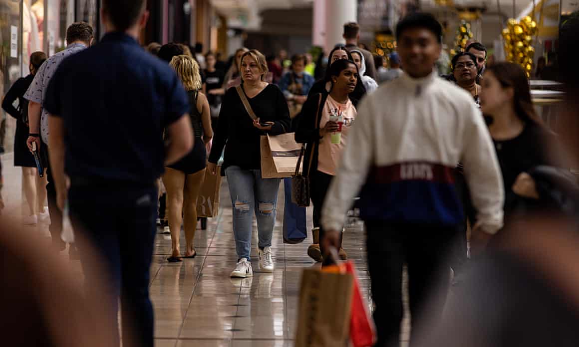 Multiple people walk in a shopping mall with the ones in the foreground blurred