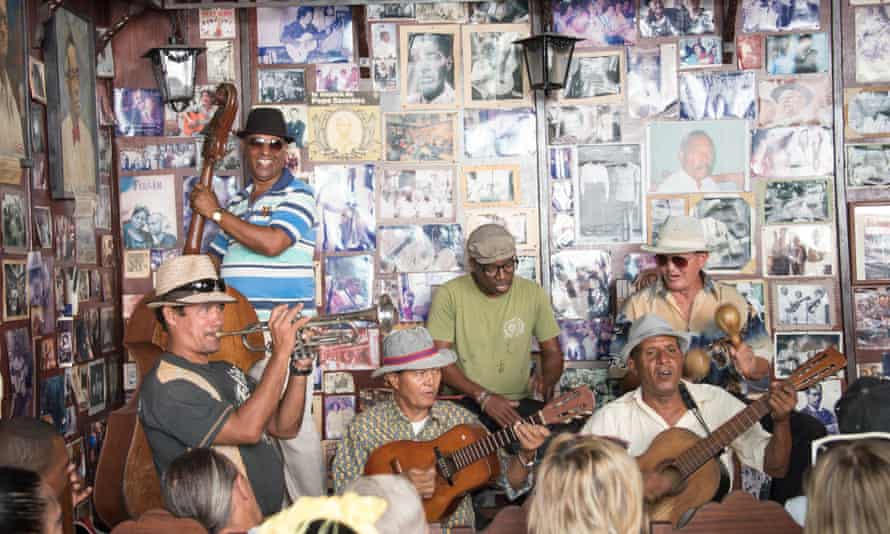 Musicians playing their instruments in front of a wall covered with photos at Casa de la Trova, Santiago de Cuba, Cuba.