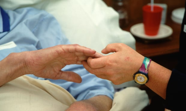Hospice worker holding hand of patient