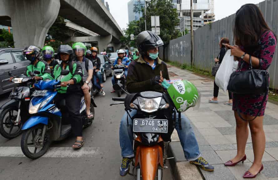 A motorcycle taxi for smartphone app Go-Jek picks up a customer.