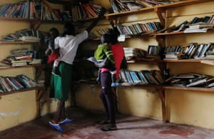 Teenage mothers carry their children inside a library as they collect books
