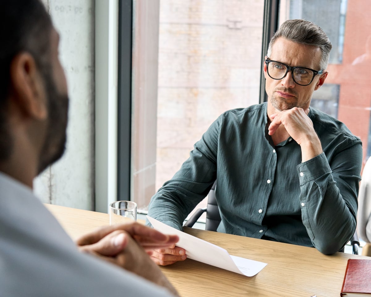 Serious businessman holding CV listening to applicant at job interview