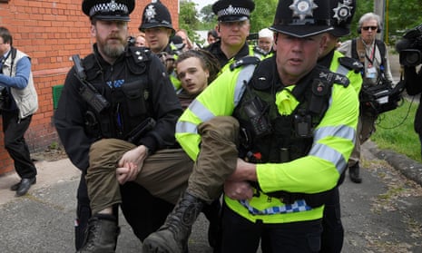 Police officers carry a man away from an election campaign event being held by Theresa May in Wrexham.