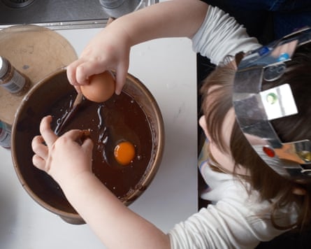 a kid successful a silver-coloured insubstantial crown cracking eggs into a vessel of cocoa barroom batter