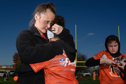 A woman hugs a girl in an orange jersey