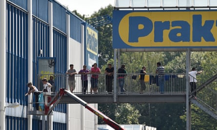 Asylum seekers stand on the steps of the new shelter in Heidenau, set up in a disused DIY store